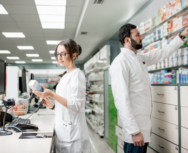 Man and woman pharmacists working at the cash register of the modern pharmacy store