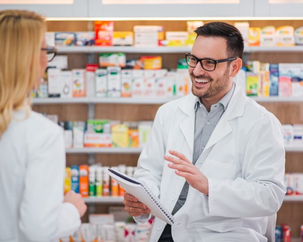 Cheerful pharmacist talking to his female colleague.